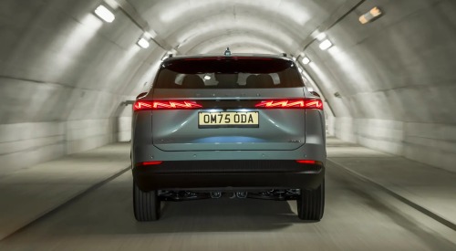 Rear view of a new OMODA 7 travelling at speed down a lit tunnel, having a focus on the rear LED lighting.