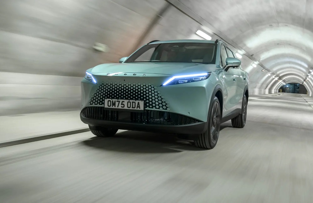 Front angled view of a new OMODA 7 going at speed down a lit tunnel, with a focus on the front LED lights and unique grille.