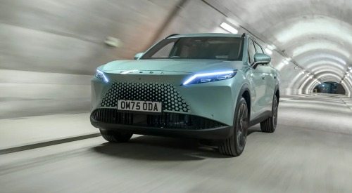 Front angled view of a new OMODA 7 going at speed down a lit tunnel, with a focus on the front LED lights and unique grille.