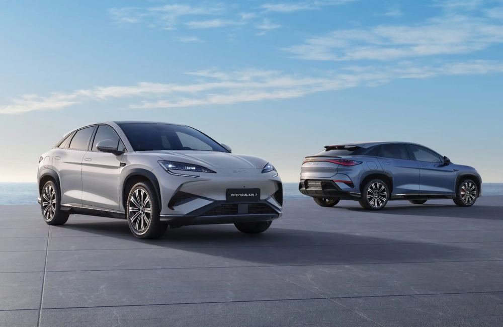 Two used BYD cars parked near one another with a scenic sunrise backdrop. One car is at a forward angle, with the other showing off an angled side shot