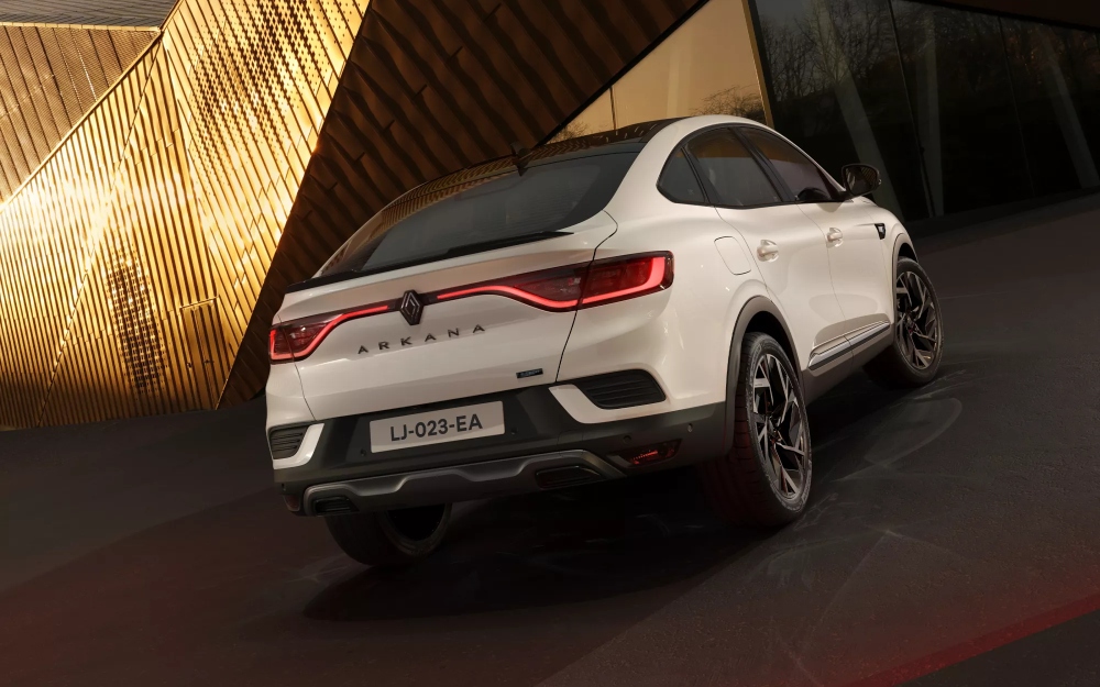 Rear view of a white Renault Arkana with LED tail lights outside a modern building.