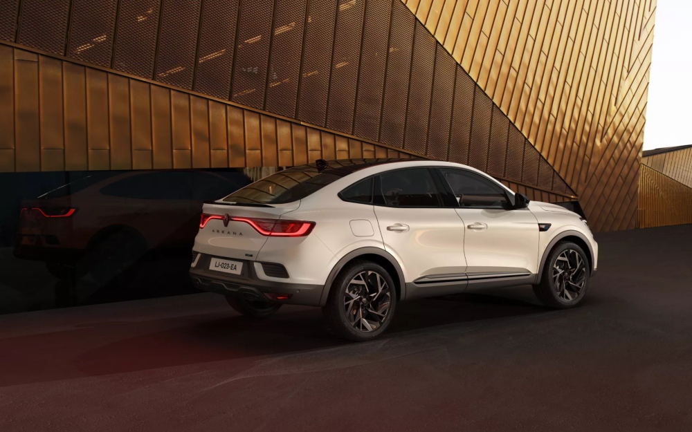 Side view of a white Renault Arkana parked outside a modern building.