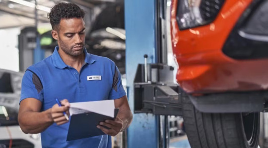 A Ford technician checks his paperwork in a workshop
