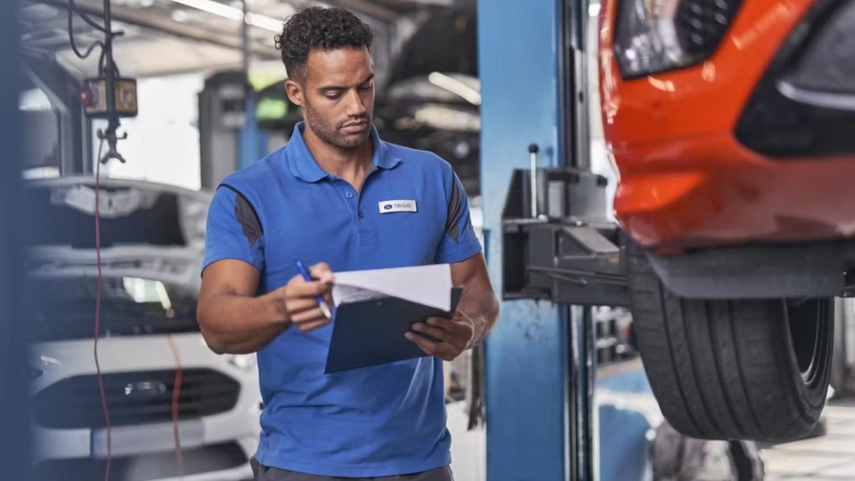 A Ford technician checks his paperwork in a workshop