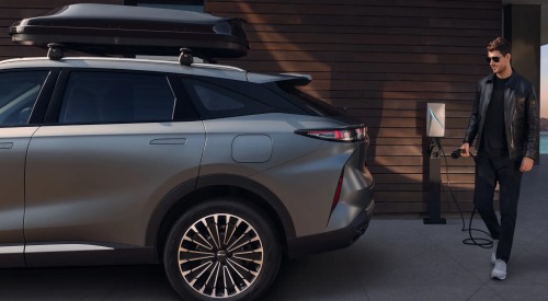 Back side of an OMODA 9, with a person walking up holding a charger in prep to charge the internal battery.