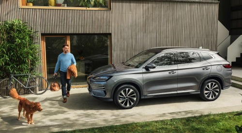 A person and dog walk out of their house to get into their BYD SEAL U DM-i hybrid car which is parked outside.