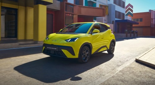 A vibrant yellow coloured BYD DOLPHIN SURF cruising down a futuristic city scape