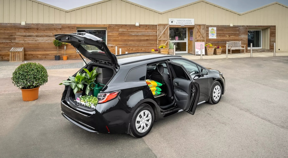Toyota Corolla Commercial in black, parked outside a garden centre with its boot open.