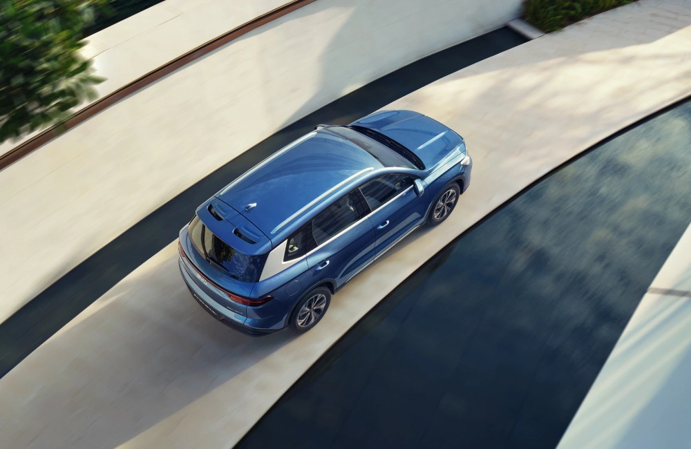 Angled top-down view of a BYD SEALION 5 DM-i moving at speed along a road.