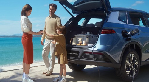 A family consisting of two adults and one child, parked up near the beach and having a drink from a coffee machine powered by the internal battery of their BYD SEALION 5 DM-i.