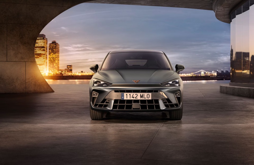 Front view of a CUPRA Leon, with a cityscape background. Focus is on the front grille and unique look the car has to offer.