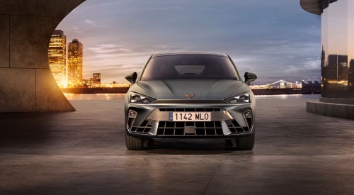 Front view of a CUPRA Leon, with a cityscape background. Focus is on the front grille and unique look the car has to offer.