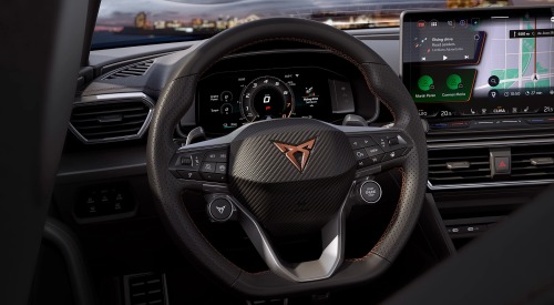Interior view of the CUPRA Leon Estate, from the perspective of the drivers seat, showing off the infotainment system, steering wheel, and digital cluster.