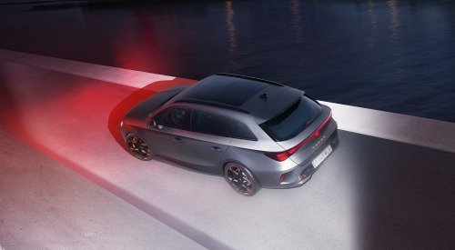 Side profile of a CUPRA Leon Estate in a futuristic setting, with blue and red lighting