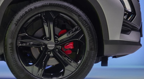 Close up view of an OMODA 5 black alloy wheel, boasting red brake caliper and OMODA branding.
