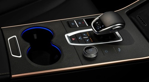 Front centre console of an OMODA car, showing cupholders, drive mode changer, central gear shifter, and multiple controls