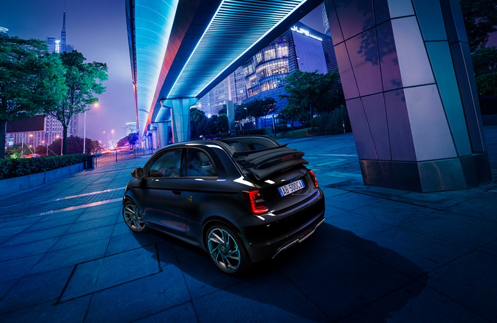 Angled rear view of an Abarth 500e Cabrio, with the convertible roof lowered.