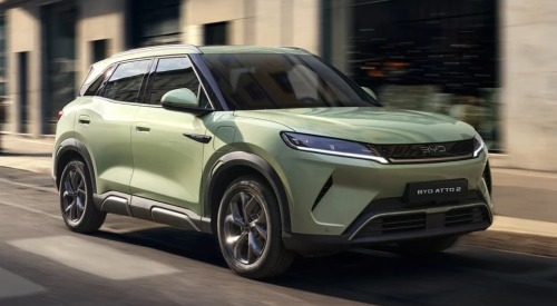 A BYD ATTO 2 going at speed down a city street, shown from an angled front view.