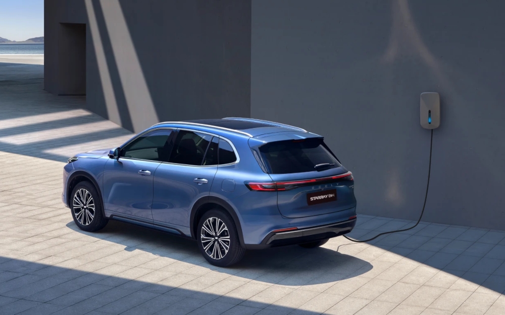 Geely Starray EM-i plug-in hybrid SUV in blue charging at a home wall box.