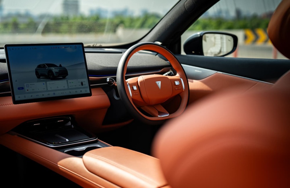 Interior view of the Changan Deepal S05, showing off the orange detailing and driver cockpit. The central screen shows information about the car.