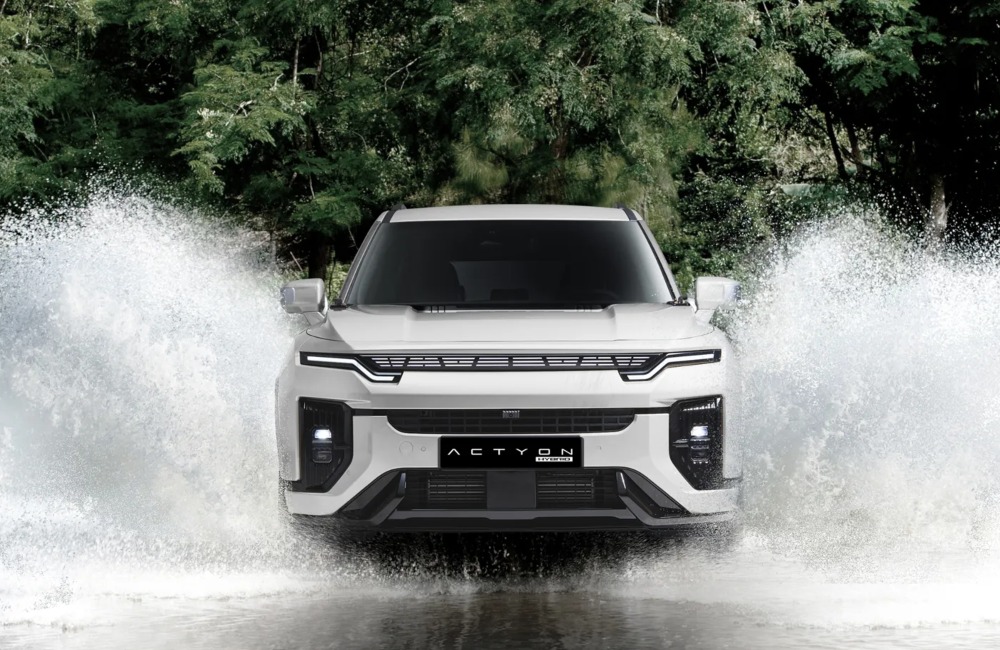 KGM Actyon Hybrid driving through water, splashing the water outward from the car on both sides.