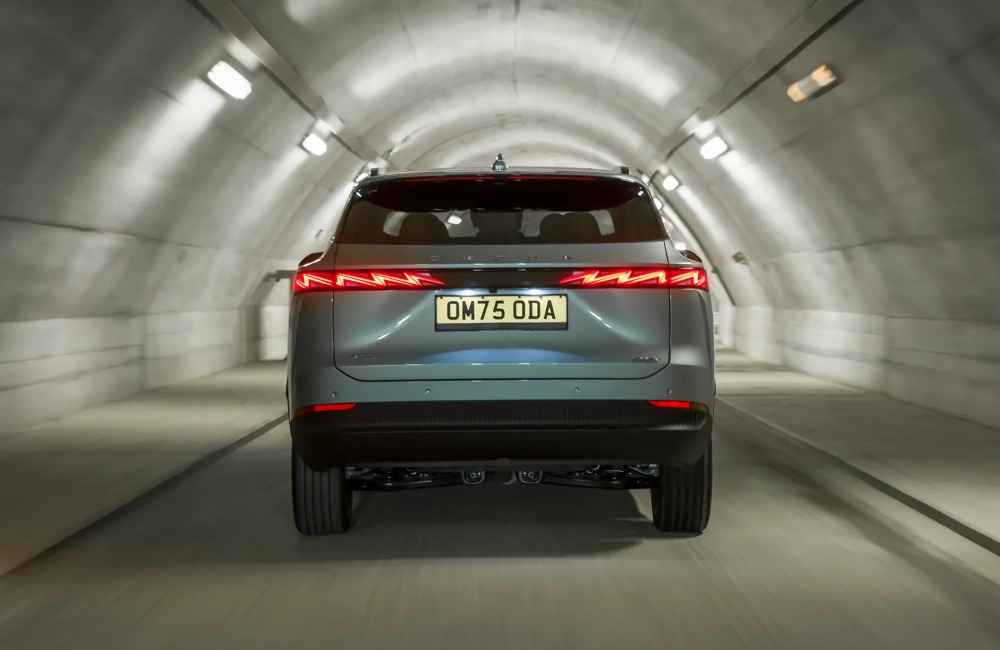 Rear view of an OMODA car travelling at speed down a lit tunnel, having a focus on the rear LED lighting.