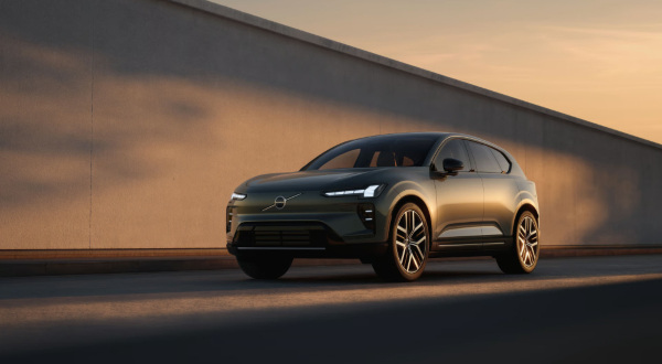 Front three-quarter view of the Volvo EX60 in Forest Lake driving alongside a concrete wall.